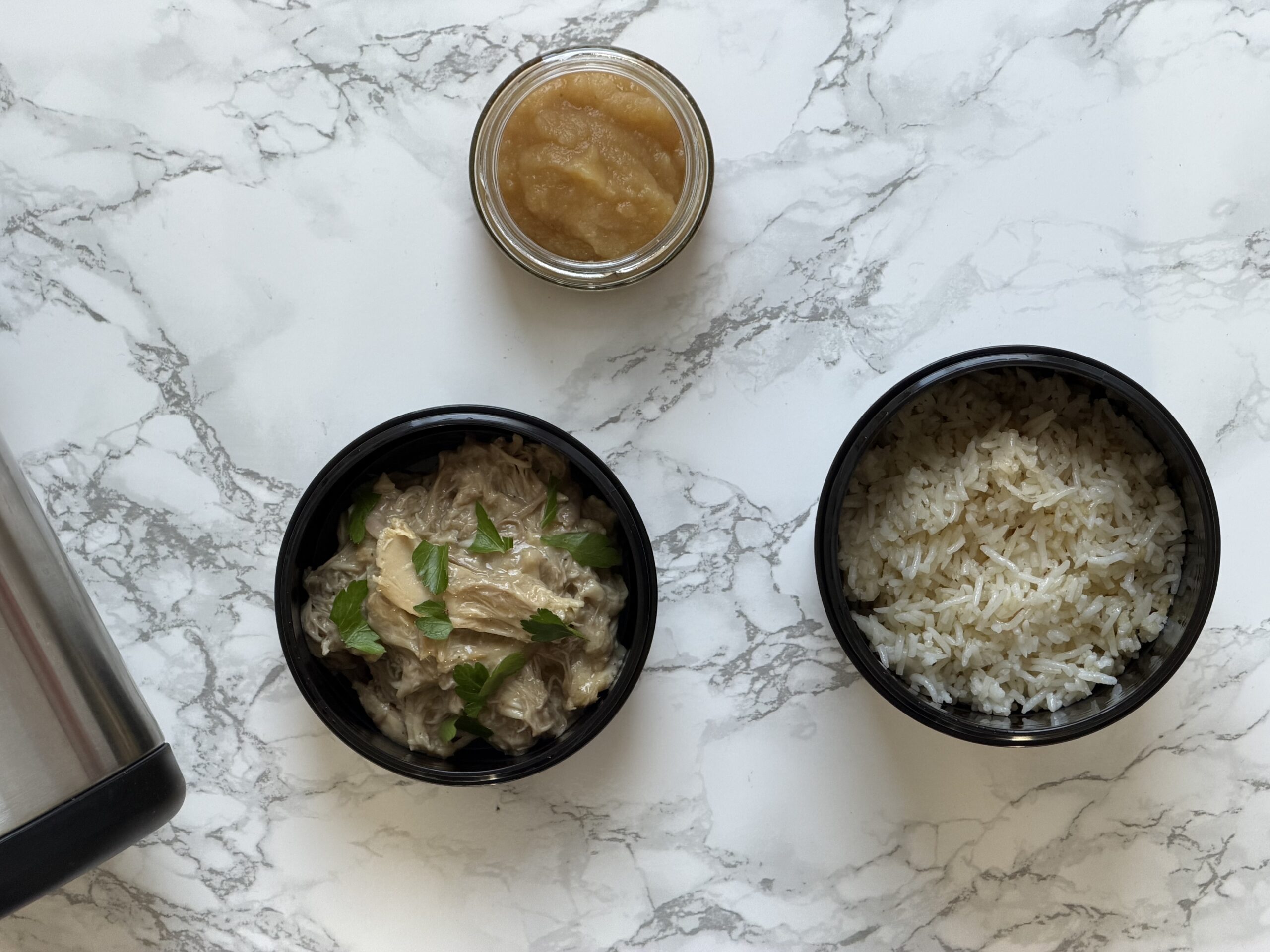 Zwei Behälter einer Thermo Lunchbox gefüllt mit Reis und Hühner Ragout auf weißem Marmoruntergrund