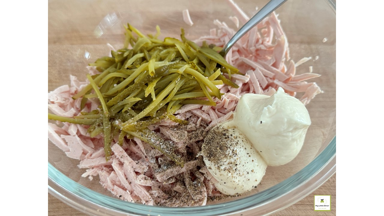 Bild zeigt Rezept Fleischwurst Salat - Zubereitungsschritt 2 - Streifen von Wurst und Gurken mit restlichen Zutaten
