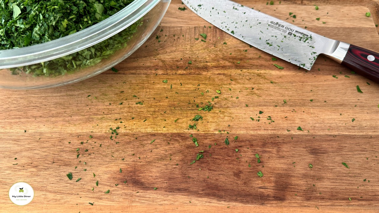 Holzbrett zeigt nach dem Hacken von frischen Kräutern mit einem scharfen Messer kaum ausgetretenen Saft