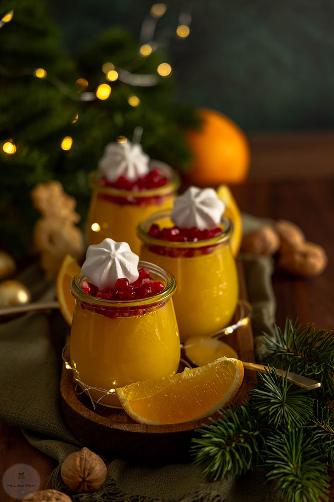 Erfrischendes Orangen Gelee in drei Dessertgläsern steht weihnachtlich dekoriert auf einem Holzbrett