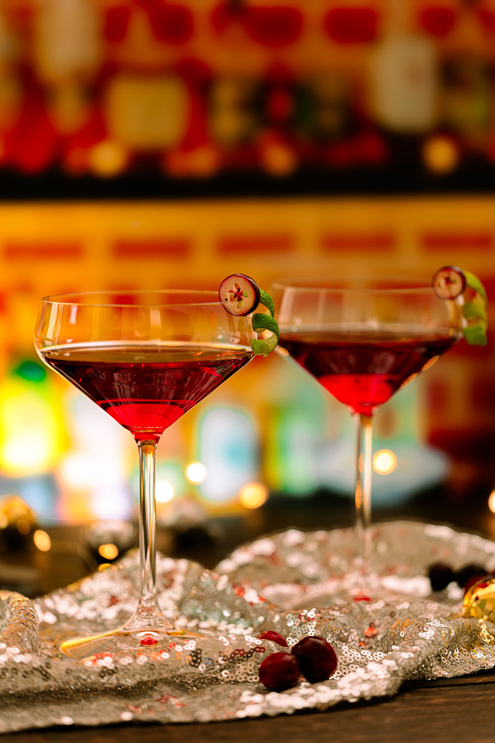 Zwei Cocktailgläser mit rotem Getränk stehen auf einem Bartresen und werden von hinten angeleuchtet