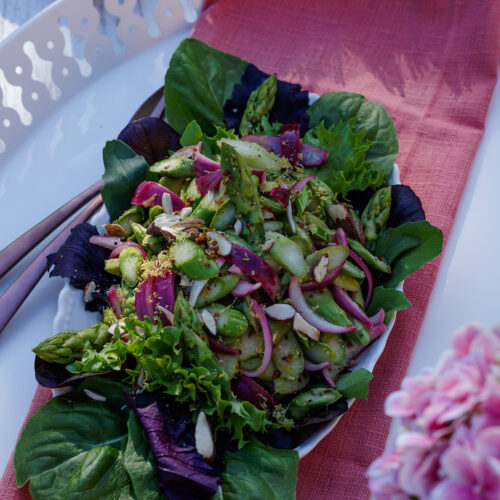Rezept-Bild für grünen Spargelsalat der sommerlich dekoriert auf einem weißen Teller angerichtet ist